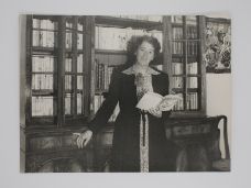 SIGNED ORIGINAL PHOTOGRAPH OF ENID BLYTON STANDING IN FRONT OF THE BOOKS SHE HAS WRITTEN